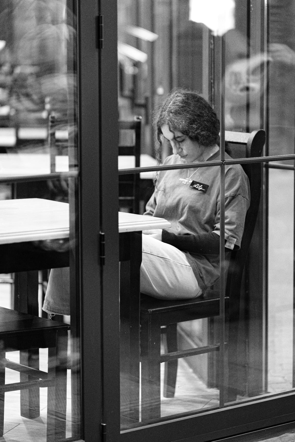 A reader with an open book beside a café window.