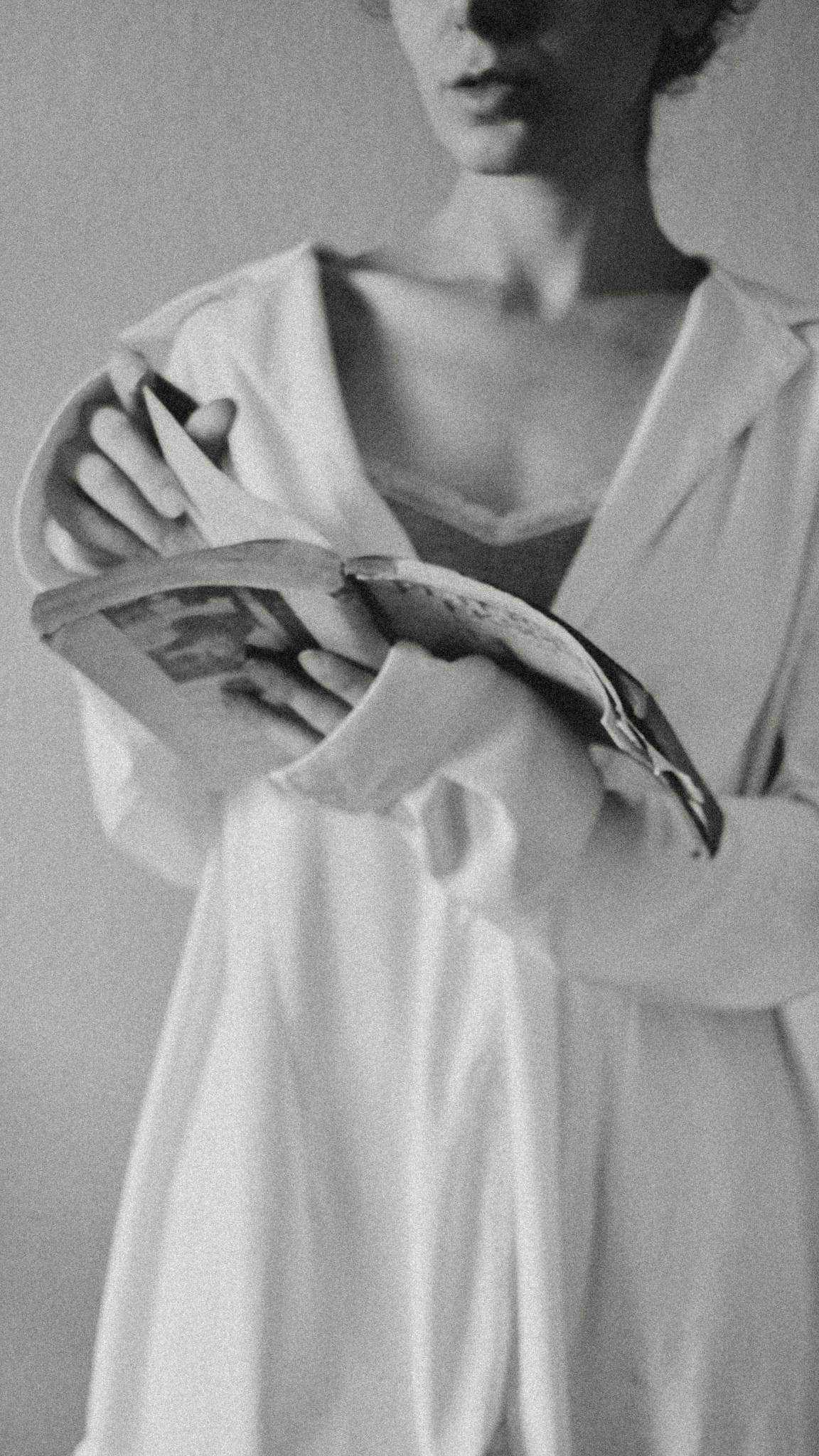 A reader in a white shirt holding an open book.
