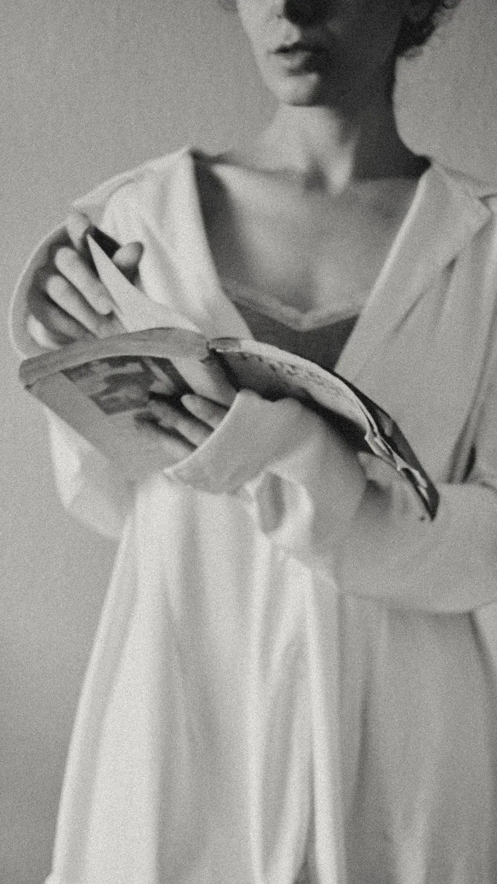 A reader in a white shirt holds an open book.